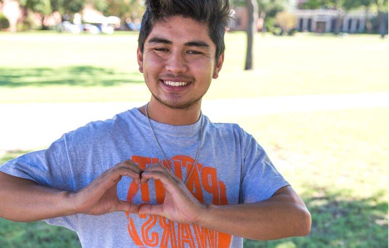 A student making a heart shape with his hands to thank donors.