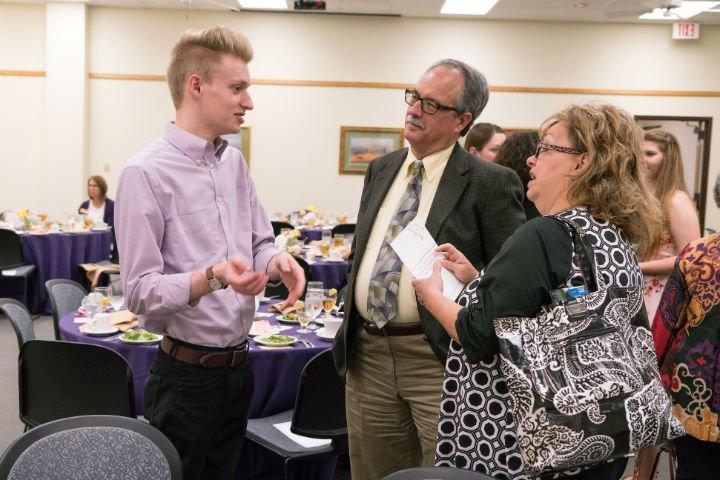 A student talking to scholarship donors at a luncheon.