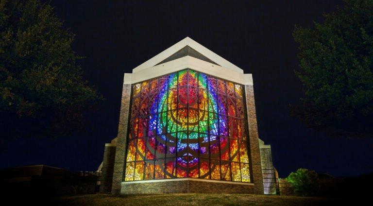 The Logsdon Chapel stained glass window shines brightly at night.